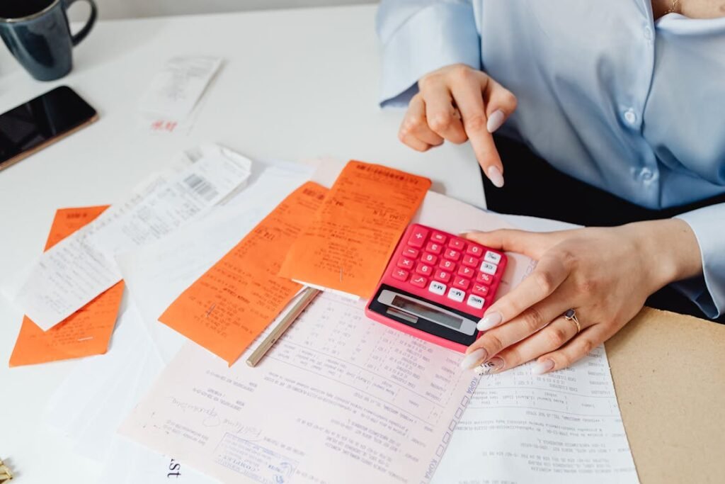 A person reading receipts and using a handheld calculator