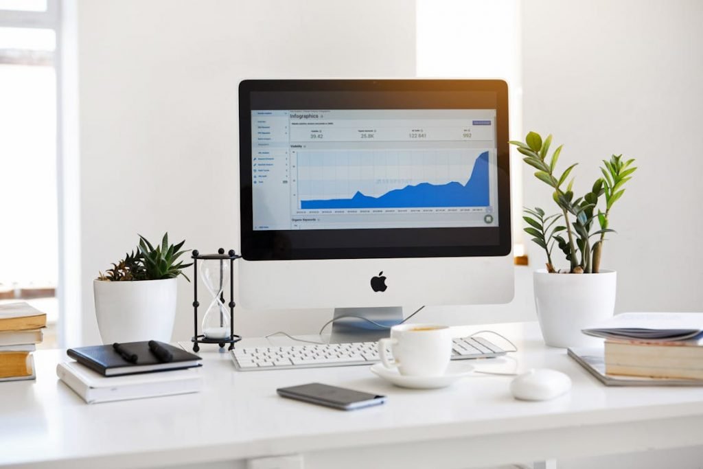 A computer desk with a monitor and a cup of tea 